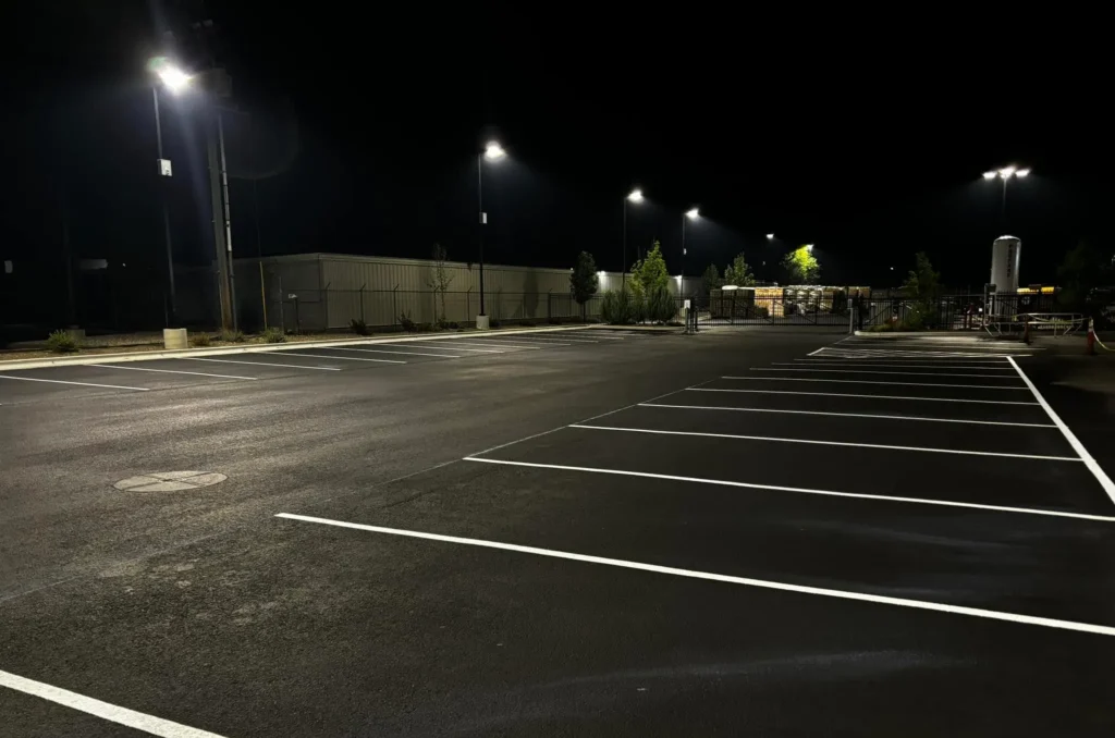 Freshly paved and striped parking lot illuminated by bright streetlights at night.