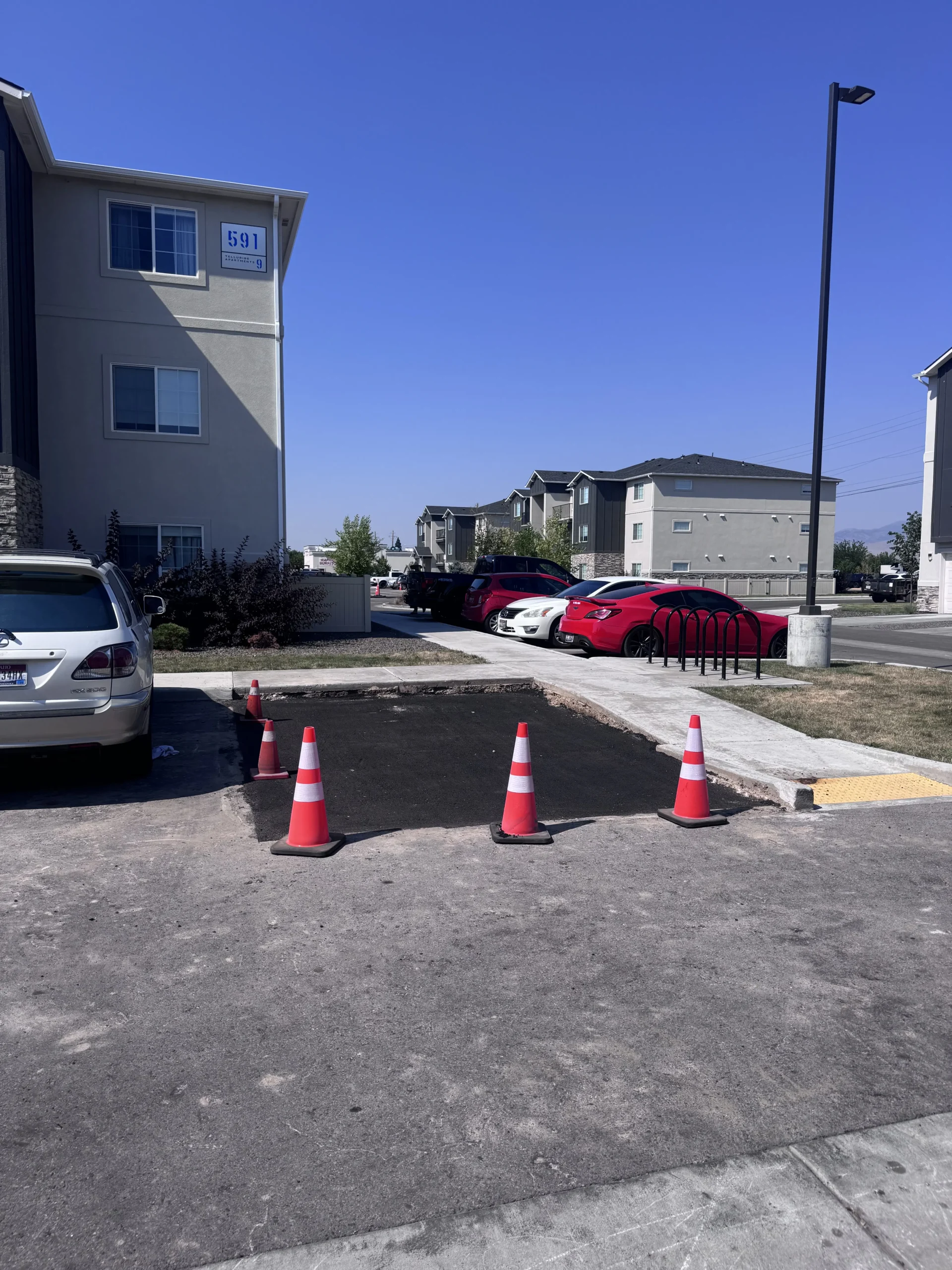 Fresh asphalt patch protected by traffic cones at an apartment property